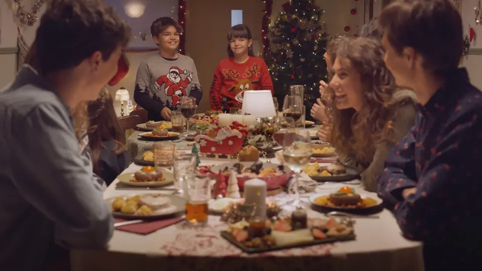 Cena de Navidad en familia alrededor de una mesa llena.