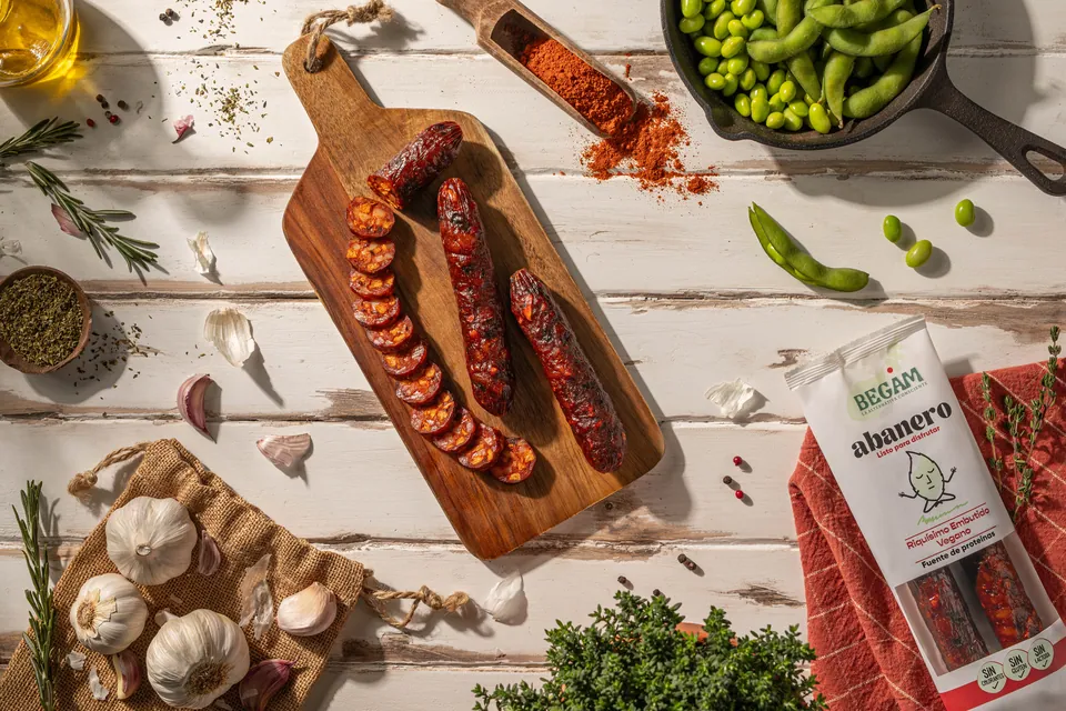 Chorizo vegano sobre tabla de madera con especias y legumbres.